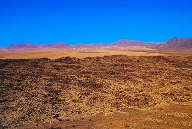 Volcanic landscape with volcanoes in background near Tiscamanita, Fuerteventura, Canary Islands, Spain