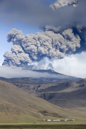 Houses at foot of mountains with the ash plume of the Eyjafjallajokull eruption in the distance, southern area, Iceland, Polar Regions