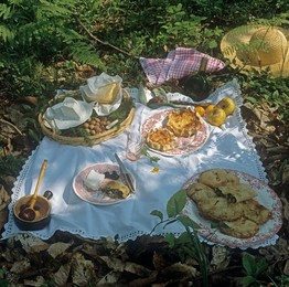 Outdoor eating of picnic with plates of food spread out on white cloth