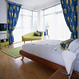 Double bed in double aspect bedroom with vibrant blue and green curtains