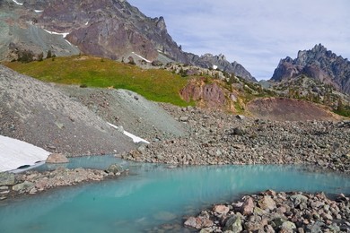Tarn colored aqua by glacial flour in the cirque of Royal Basin, looking toward Mt. Clark and The Needles, in Olympic National Park, Washington State, USA.