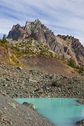 Tarn colored aqua by glacial flour in the cirque of Royal Basin, looking toward Mt. Clark and The Needles, in Olympic National Park, Washington State, USA.