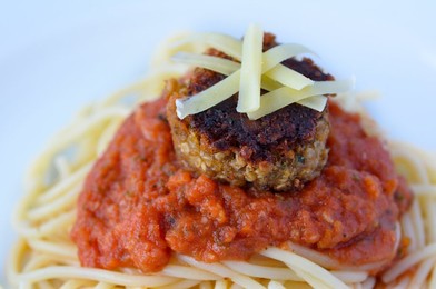 Close up of lentil meatball with burst tomato pasta