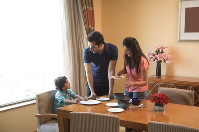 Mother and father serving food to son at dinning table