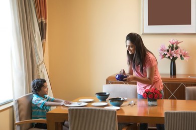 Mother serving food to son at dinning table