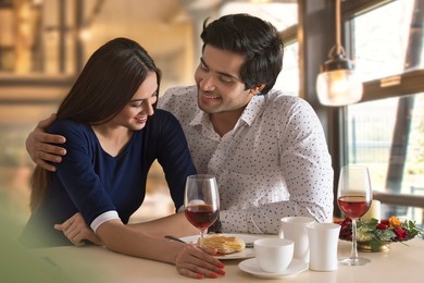 Happy young couple having food at restaurant table