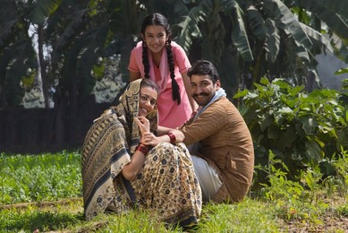 Happy and smiling rural family sitting in their agriculture field.