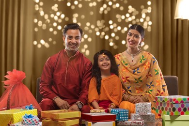 Happy family sitting on a sofa with presents on diwali