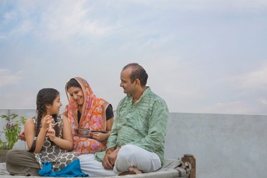 Portrait of happy Indian family sitting on a camp bed