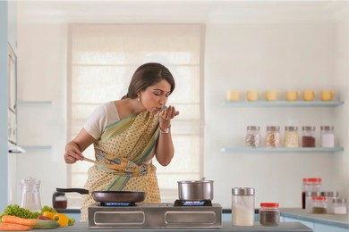 woman tasting food on hand while preparing it