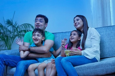 Happy family with popcorn watching TV on sofa