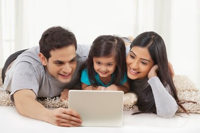 Happy family lying on floor using digital tablet