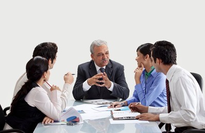 Mature businessman conversing with staff in meeting