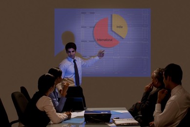 Young businessman presenting on projection screen in meeting