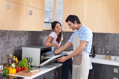 Beautiful woman looking at man preparing food in kitchen