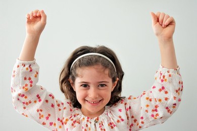 Happy young girl holding hands up looking at camera
