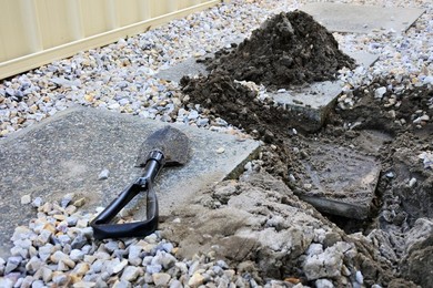 Shovel laying beside a hole  with underground water pipe leak
