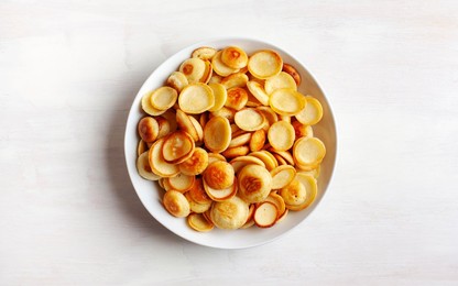 Trendy food - pancake cereal. Heap of mini cereal pancakes in boul. View from above.