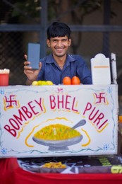 Portrait of happy street vendor showing his smartphone