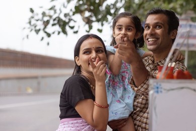 Portrait of happy family standing near street shop