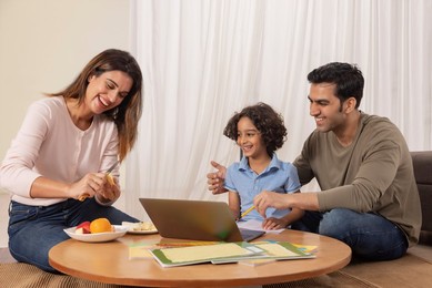 Woman cutting healthy fruits for her husband and son while doing homework