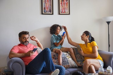 Happy nuclear family using smartphone in living room
