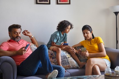 Happy nuclear family using smartphone in living room