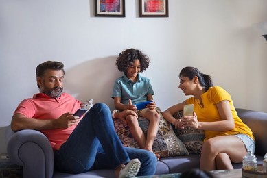 Happy nuclear family using smartphone in living room