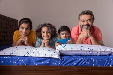 Portrait of happy family lying down together on bed