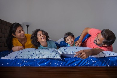 Portrait of happy family having fun together on bed