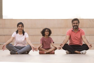 Portrait of happy family meditating together at outdoor in the morning