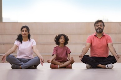 Portrait of happy family meditating together at outdoor in the morning