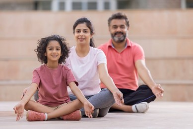 Portrait of happy family meditating together at outdoor in the morning