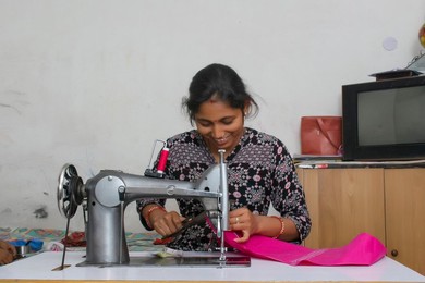 happy woman working on sewing machine as tailor