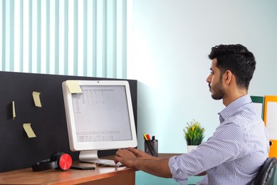 A corporate employee entering records in the computer at his workdesk.