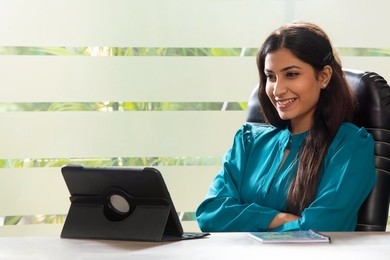 A YOUNG WOMAN HAPPILY ATTENDING A MEETING OVER VIDEO CONFERENCING