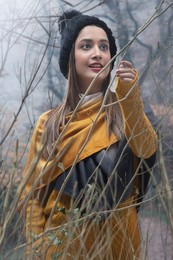 A YOUNG WOMAN HAPPILY POSING AMIDST NATURE ON A CHILLY DAY