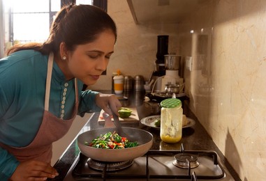 Woman smelling food while cooking in kitchen