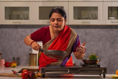 Young woman smelling food while cooking in the kitchen