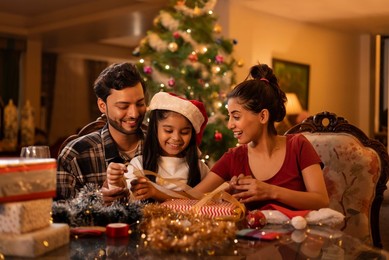 Happy family wrapping Christmas presents together at home