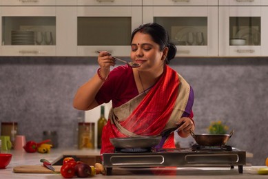 Young woman smelling food while cooking in the kitchen
