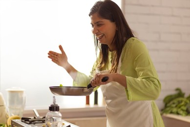 Woman smelling food while cooking in kitchen
