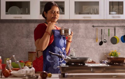 Woman with eyes closed tasting food in the kitchen