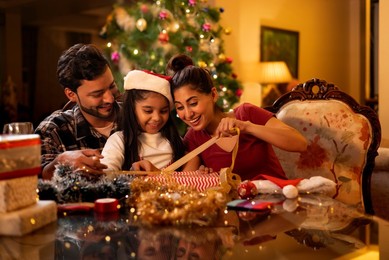 Happy family wrapping Christmas presents together at home