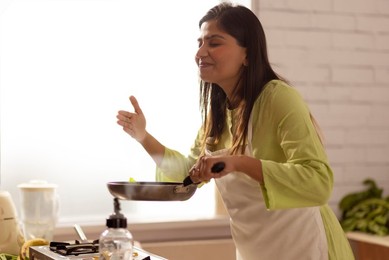 Woman smelling food while cooking in kitchen