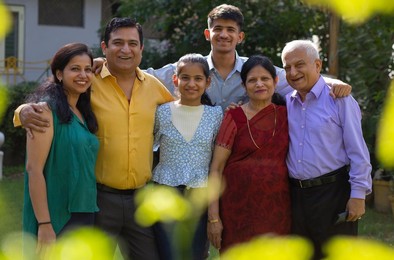 Multi generation happy Indian family standing together in backyard