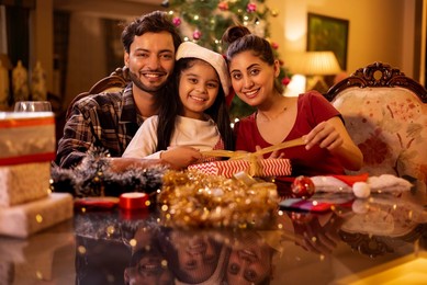 Happy family wrapping Christmas presents together at home