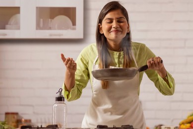 Woman smelling food while cooking in kitchen