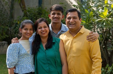 Portrait of happy Indian family standing together in backyard