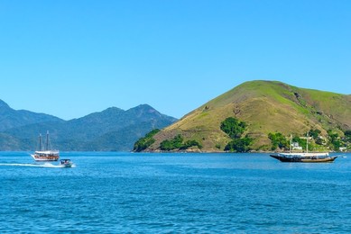Angra dos Reis, Brazil, Diverse nautical vessels and ships by scenic hills in a natural cove or bay. Angra dos Reis is a popular travel destination in South America